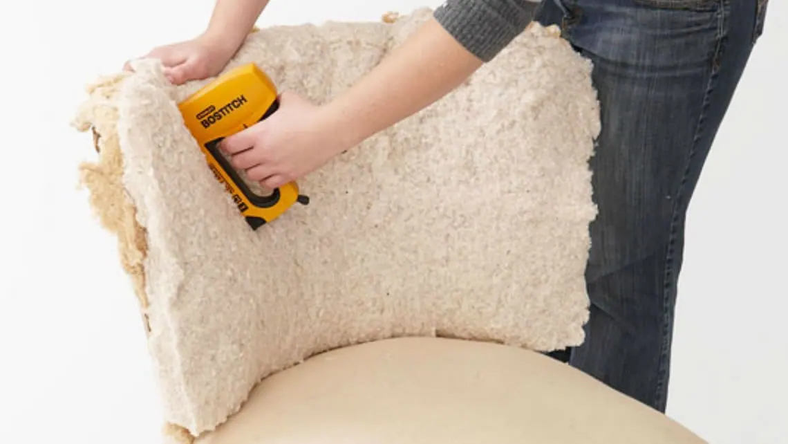 Umuntu unamathisela ungqimba lwe-upholstery ngemuva kwesihlalo nge-stapler yesandla